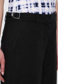 Black pants with a smooth texture, featuring a synthetic buckle belt and two side pockets, tailored fit, and minimalist design.
