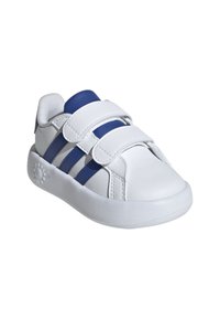 Zapatilla blanca con acentos azules, material de cuero sintético, dos correas de Velcro, puntera redondeada y una suela acolchada con detalles texturizados.