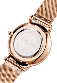 Round watch with a rose gold stainless steel case and mesh strap. Back features engraved text; water-resistant to 3ATM.
