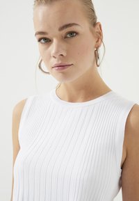 Witte geribbelde mouwloze top met een ronde halslijn, met een gladde textuur en een slim fit, waardoor een casual maar verfijnde uitstraling ontstaat.