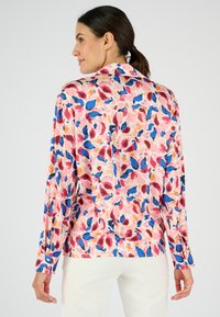 Camicia a maniche lunghe con un motivo astratto in rosa, blu e rosso, dotata di colletto e polsini con bottoni. Tessuto dalla consistenza liscia.