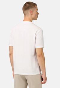 T-shirt bianca a girocollo realizzata in soffice tessuto, caratterizzata da maniche corte, vestibilità rilassata e una texture liscia. Vista dal retro.
