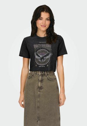 Camiseta gráfica negra con diseño de un búho y texto "Nocturnal" combinada con una falda de mezclilla de cintura alta y deslavada en color verde oliva.