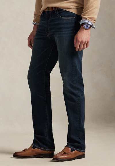 Temno modre kavbojke z ravnimi hlačnicami, srednje težka tkanina, rahlo šivanje, nošene s svetlo rjavimi loafer čevlji.