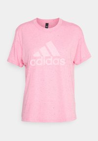Vaaleanpunainen puuvillainen T-paita, jossa on pilkullinen tekstuuri, iso valkoinen Adidas-logo ja pyöreä pääntie. Lyhyet hihat ja rento istuvuus.