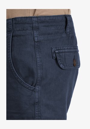 Marineblaue Baumwollhose mit glatter Textur, ausgestattet mit Seitentaschen und einer geknöpften Pattentasche auf der Rückseite, mit gestickten Details entlang der Nähte.