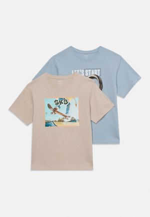 Deux T-shirts à manches courtes, l'un beige avec un graphisme de skateur et le texte "SK8", l'autre bleu clair avec le texte "LET'S START" et une illustration de skateboard.