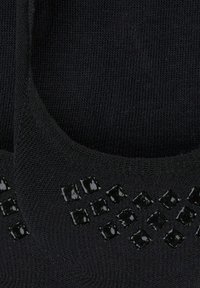 Schwarze Stricksocken mit einem Diamantmuster aus glänzenden schwarzen Akzenten an einer Seite, die eine glatte Textur aufweisen.