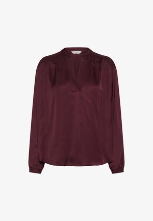 Burgundy selyem blúz, V-nyakkivágással, hosszú ujjal, rugalmas mandzsettával és laza szabással. Simább textúra, minimális részletezéssel.