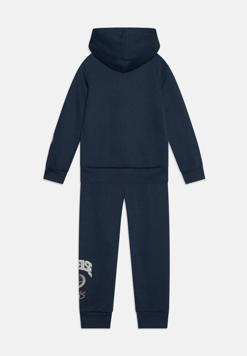 Set di felpa e pantaloni tuta di colore blu navy, realizzato in materiale morbido, con cappuccio, polsini a coste e un design con logo sulla gamba sinistra.