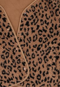Leopardprint fleece omslag met zwarte vlekken op een tan achtergrond, voorzien van een beige afwerking en drukknopen om te sluiten. Zachte textuur.