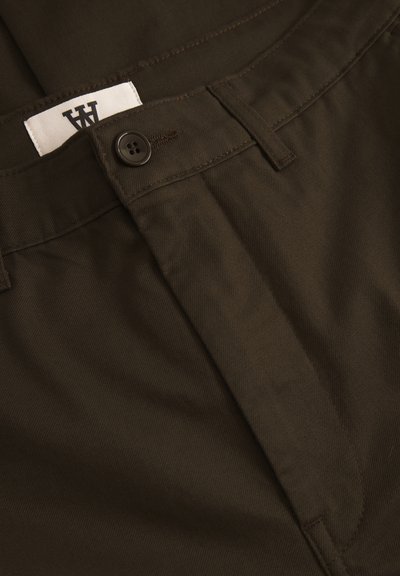 Dark brown cotton pants with a smooth texture, featuring a button closure and a white label with black text on the waistband.