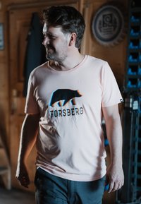 Lichtroze T-shirt met een zwarte beer grafiek en de tekst "FORSBERG". Korte mouwen, ronde halslijn, gemaakt van zachte stof, casual pasvorm.