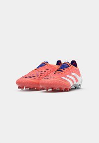 Botas de fútbol de color naranja brillante con una superficie texturizada, acentos azules y tres franjas blancas. Cuentan con tachones puntiagudos para tracción en el césped.