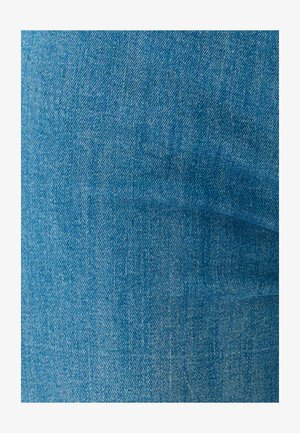 Primer plano de la textura de tela de mezclilla azul claro que muestra un patrón de tejido diagonal y pliegues sutiles.