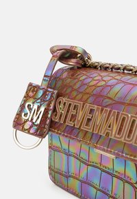 Borsa iridescente con motivo a rilievo effetto coccodrillo, tracolla in catena dorata e logo in metallo. Presenta una piccola etichetta con le iniziali "SM" attaccata.