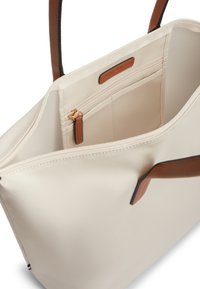 Τσάντα ώμου κρεμ με καφέ χερούλια, ανοιχτό επάνω μέρος που αποκαλύπτει εσωτερική θήκη με φερμουάρ και μπεζ υφασμάτινη επένδυση.