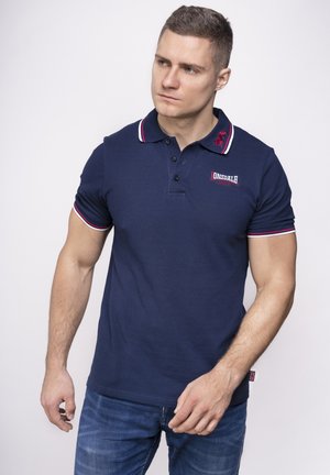 Mornarska polo majica od pamuka, sa dvostrukim dugmetom, kontrastnim prugama na ovratniku i izvezenim logom na grudima.