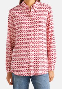 Chemise à manches longues à motif rouge et blanc, dotée d'un design géométrique et d'un col classique. Le matériau semble léger.