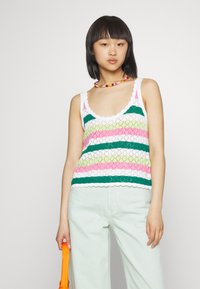 Top de malha multicolorido com riscas rosa, verde e branca, com uma borda em forma de ondas. Combinado com calças verde claro e uma bolsa laranja.