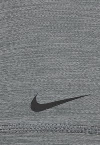 Tessuto atletico Nike in grigio scuro mélange con una texture liscia. Presenta un logo nero prominente vicino al bordo inferiore e cuciture pulite.