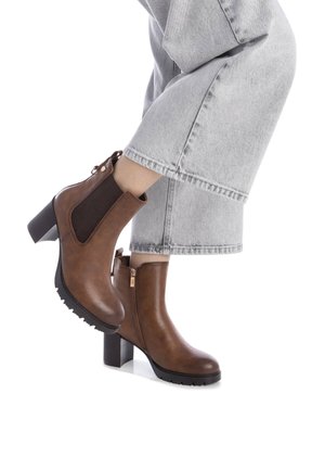 Botas de tobillo de cuero marrón con un panel lateral de punto texturizado, cremallera trasera y tacón cuadrado. La suela presenta un patrón de agarre para mayor tracción.