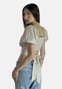 Ternet cropped bluse i beige og hvid med puff-ærmer, rynket ryg og bindedetalje i taljen. Bruges med højtaljede jeans.