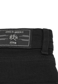 Musta farkkuvyö, jossa on etiketti "BAND OF RASCALS" ja ristikkäiset sakset -kuvio. Materiaali on sileä ja tukevan tuntuinen.