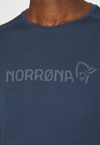 Sötétkék, rövid ujjú ing texturált anyagból, világosszürke "NORRØNA" logóval és egyszerű kerek nyakkal.