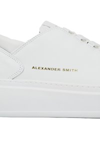 Zapatilla blanca de cuero con detalles de costura, suela plana y la marca dorada 'Alexander Smith' en el lateral. Textura suave y diseño minimalista.
