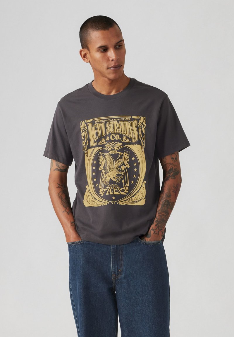 Tricou din bumbac gri închis cu un grafic galben ce prezintă "Levi Strauss & Co." și un design cu un vultur. Croială lejeră, de tip crew neck, cu manșete scurte.