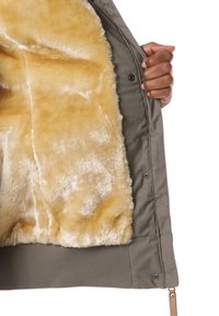 Olive zielenina kurtka z miękkim, jasnobrązowym futerkiem syntetycznym. Wnętrze jest pluszowe, a zewnętrzna część ma zatrzaski i żeberkowy dół.