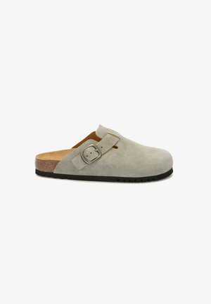 Sabot en cuir suédé gris avec un bout arrondi, sangle réglable, semelle intérieure en liège et semelle extérieure en caoutchouc noir. Design minimaliste sans logo visible.