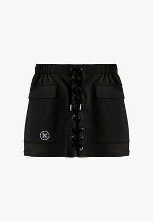 Minifalda negra con detalle de cordones en la parte delantera, dos grandes bolsillos delanteros, cintura elástica y un pequeño logo blanco redondo en el bolsillo izquierdo.