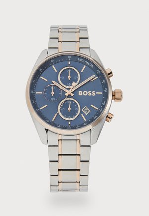 Montre chronographe avec un cadran bleu marine, bracelet en métal argenté et or rose, trois sous-cadrans et un affichage de la date �à 4 heures.