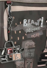 Braune synthetische Handtasche mit besticktem Stadtbild, die bunte Akzente und einen dekorativen Anhänger in Form einer Miniaturtasche aufweist.