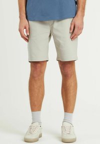 Pantaloni scurți gri deschis, fabricați dintr-un material neted, având un design drept și fără buzunare vizibile. Purtați cu adidași albi și șosete gri.