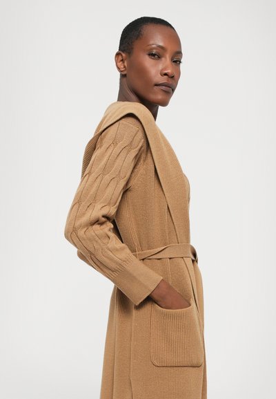 Ανοιχτό καφέ πλεκτό cardigan με ζώνη στη μέση, κωδικοποιημένα μανίκια με υφή και πλαϊνές τσέπες, που διαθέτει μια χαλαρή σιλουέτα.