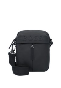 Sac crossbody noir en matériau synthétique lisse. Présente un logo en relief, une fermeture zippée et une bandoulière ajustable. Forme rectangulaire compacte.