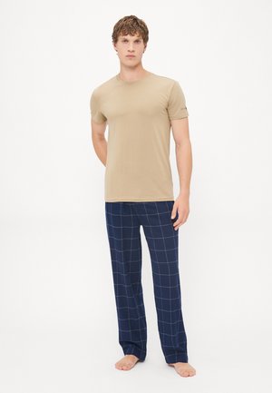 Beige Baumwoll-T-Shirt, kombiniert mit navyblauen karierten Schlafanzughosen mit weißen Gitterlinien, entspannter Schnitt und ohne sichtbare Logos oder Akzente.