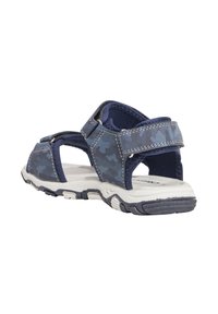 Sandali in camo blu con design aperto; cinturini regolabili; suola in gomma testurizzata; interno imbottito; accenti bianchi e blu navy.