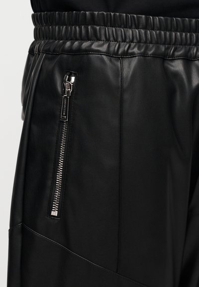 Černé kožené kalhoty s elastickým pasem se shromážděním, boční kapsou na zip a hladkou texturou s elegantním, přiléhavým střihem.