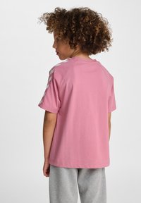 Lyserød bomulds t-shirt med korte ærmer, afslappet pasform og sølvfarvede skrå striber på skuldrene. Glat tekstur, minimalistisk design.