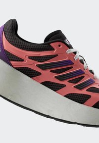 Čierne tenisky s vrchným materiálom z jemnej sieťoviny, ružovými a fialovými akcentmi, hrubou šedou podrážkou a bielymi šnúrkami; majú zakrivený dizajn a vrstvené textúry materiálov.