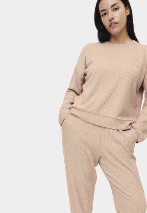 Maglione a coste beige chiaro con maniche lunghe e scollo rotondo, abbinato a pantaloni coordinati a coste con vita elastica.