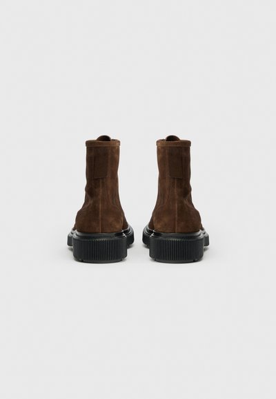 Bottes chelsea en daim marron avec un bout rond, des languettes et une semelle en caoutchouc noir texturé. Présente une finition lisse et un design minimaliste.