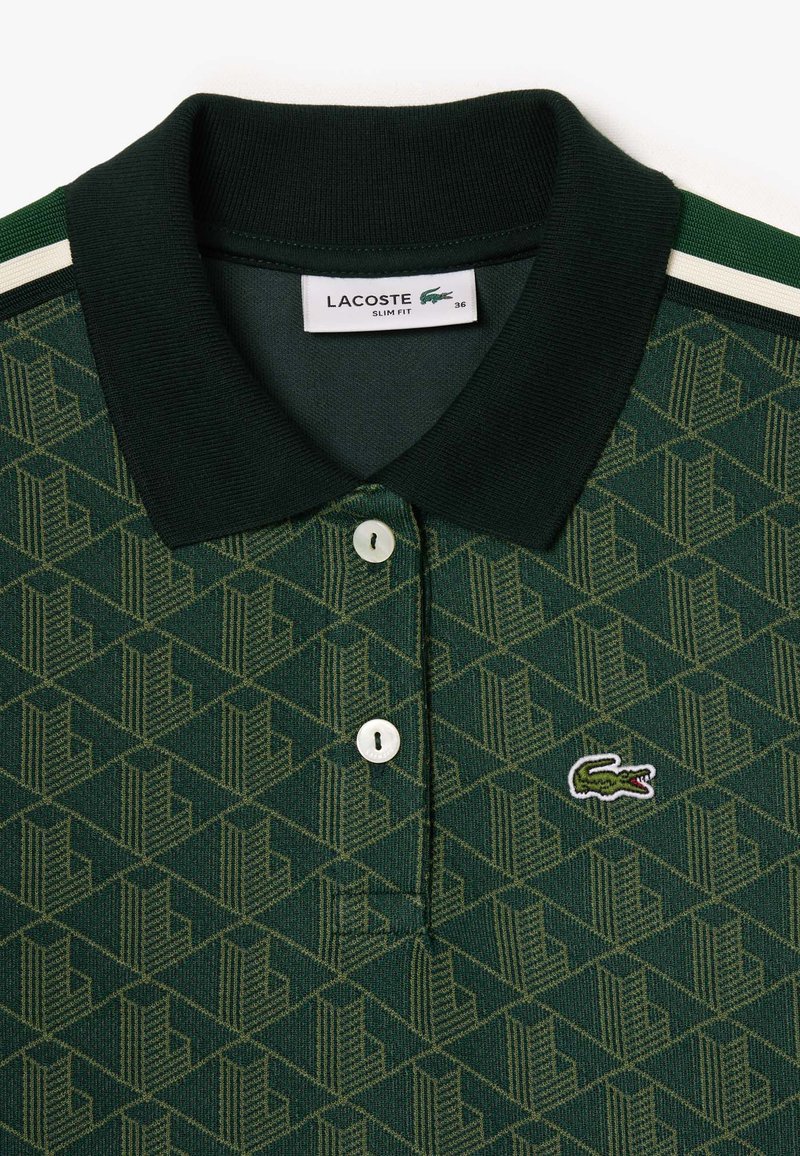 Zielona koszulka polo z geometrycznym wzorem, żebrowanym kołnierzykiem, dwoma białymi guzikami oraz haftowanym logo krokodyla. Styl slim fit.