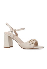 Beige hælede sandaler lavet af glat læder med lukket tå og ankelrem. Har guldspænde detaljer på forfoden og en chunky blokhæl.