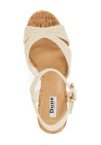 Womens sandal featuring a textured cream upper, woven strap design, a natural cork footbed, and an adjustable ankle buckle in gold.