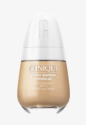 Fondotinta serum Clinique Even Better Clinical in un bottiglia trasparente con forma arrotondata. Cappuccio bianco, liquido beige, marcatura SPF 20 sull'etichetta.